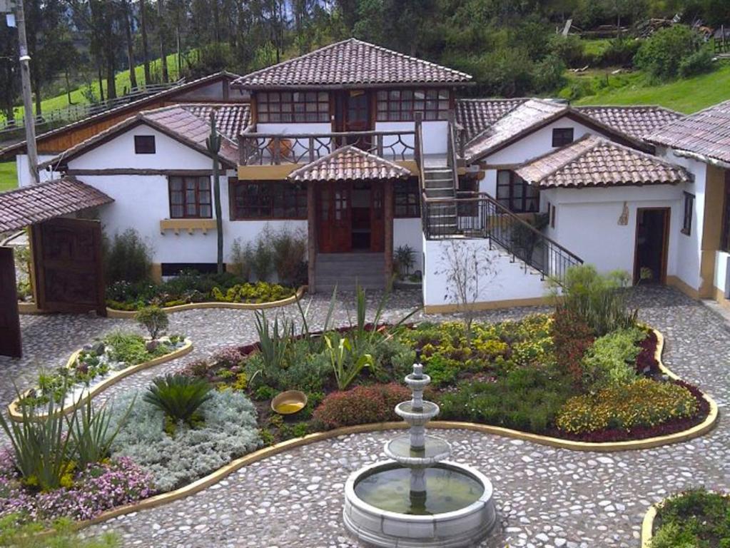 a house with a fountain in the middle of a garden at Hosteria San Jose de Sigchos in Sigchos
