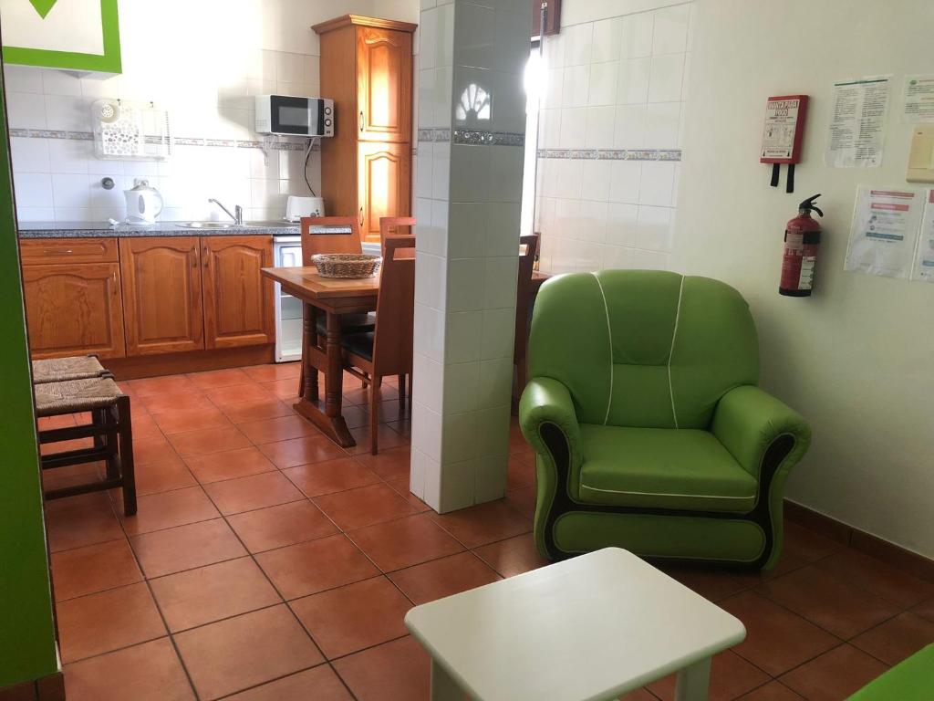 a living room with a green chair and a table at Camping Villa Park Zambujeira do Mar in Zambujeira do Mar