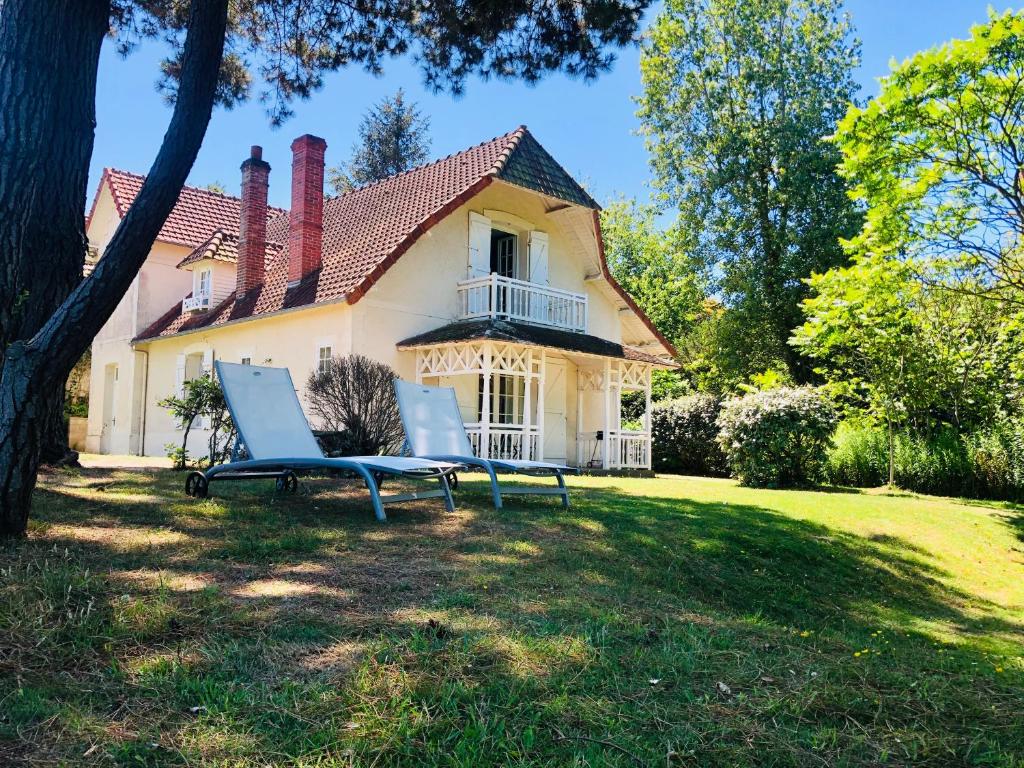 a house with two chairs sitting in the yard at Villa vue mer avec acces direct a la plage in Varengeville-sur-Mer