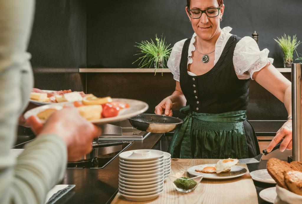 Eine Frau bereitet Essen in einer Küche zu in der Unterkunft TRAUBE BRAZ Alpen Spa Golf Hotel in Bludenz