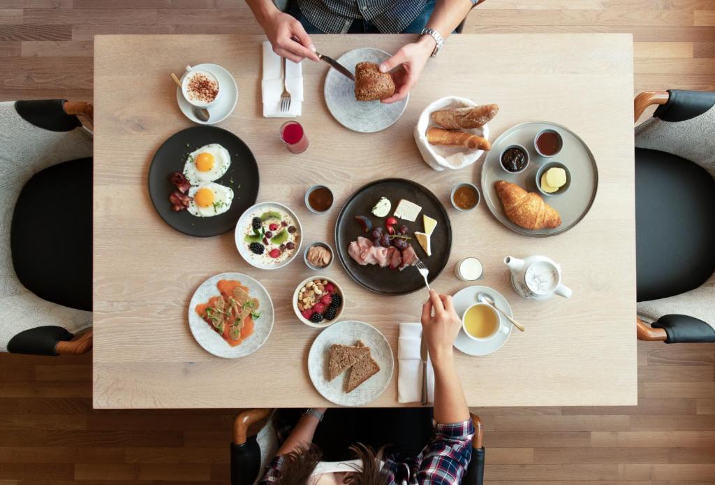 eine Gruppe von Menschen, die an einem Tisch sitzen und Frühstück essen in der Unterkunft TRAUBE BRAZ Alpen Spa Golf Hotel in Bludenz