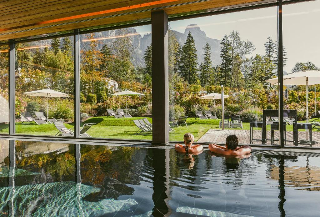zwei Personen schwimmen in einem Pool in einem Haus in der Unterkunft TRAUBE BRAZ Alpen Spa Golf Hotel in Bludenz