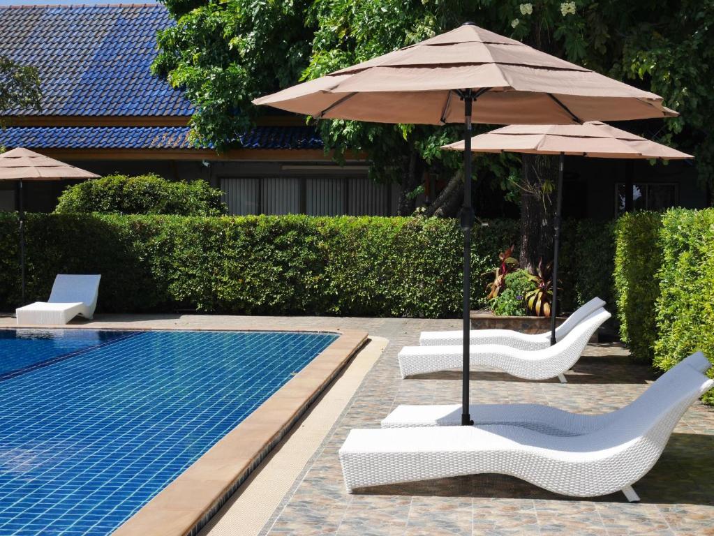 a swimming pool with two lounge chairs and an umbrella at Andaman Resort in Phi Phi Islands