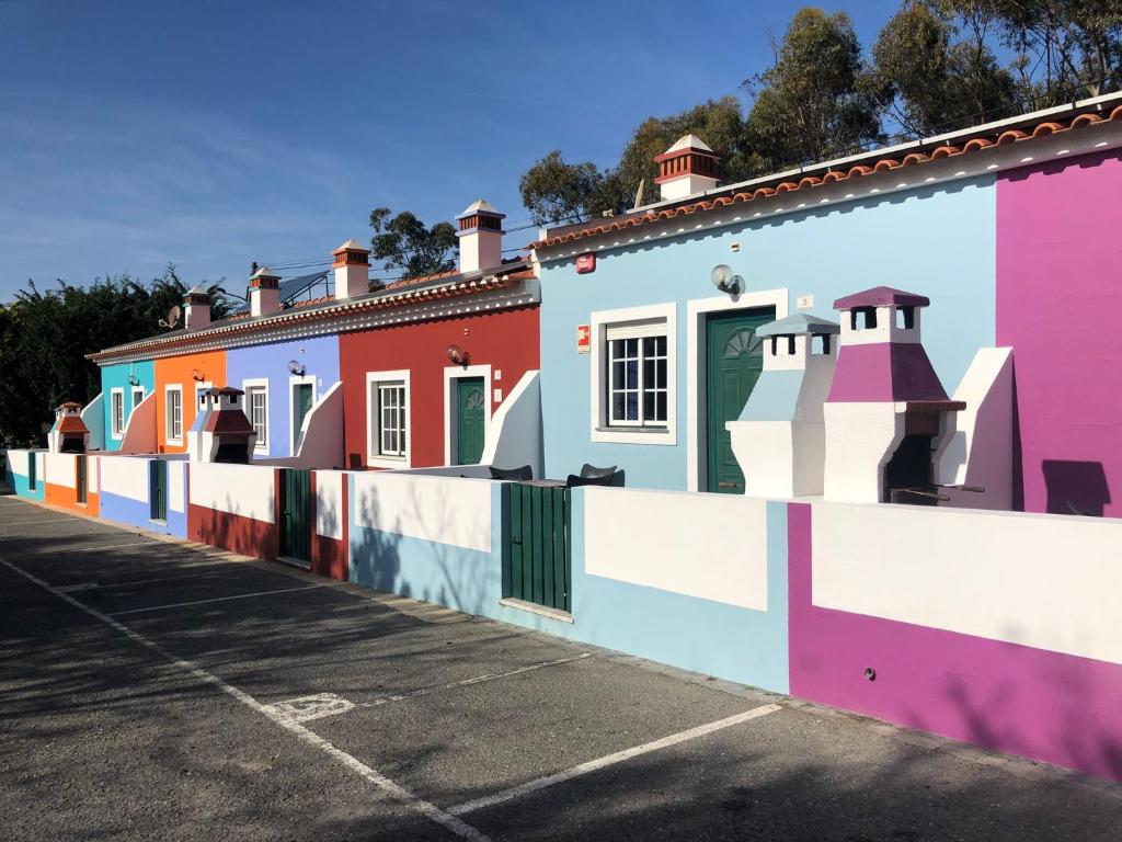 una fila de casas coloridas en un estacionamiento en Camping Villa Park Zambujeira do Mar, en Zambujeira do Mar