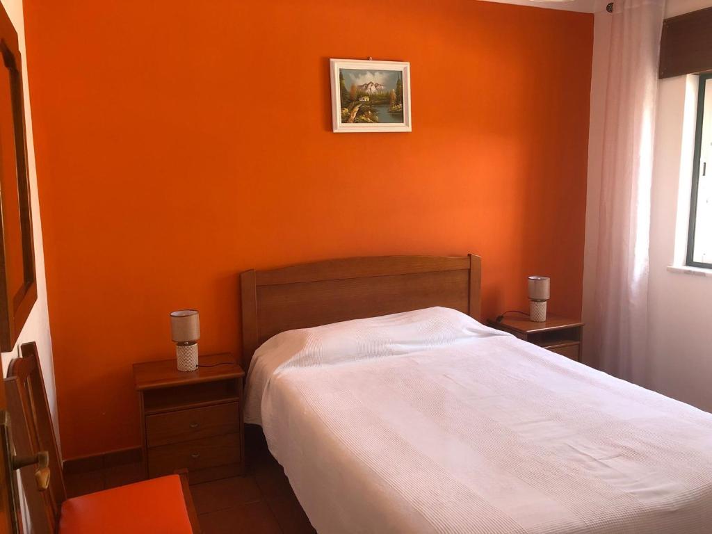 a bed in a bedroom with an orange wall at Camping Villa Park Zambujeira do Mar in Zambujeira do Mar
