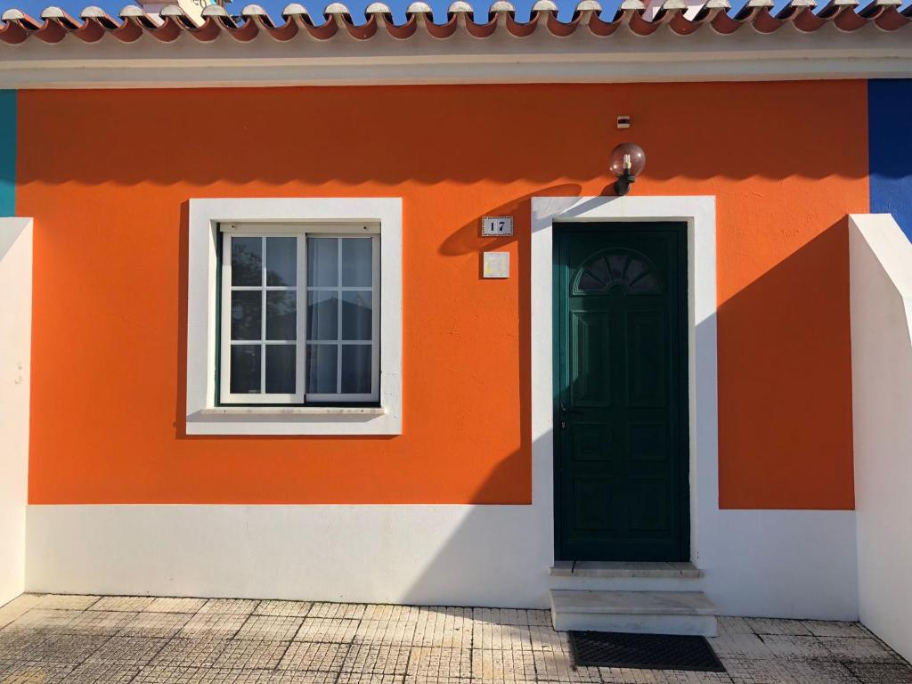 an orange and white house with a green door at Camping Villa Park Zambujeira do Mar in Zambujeira do Mar
