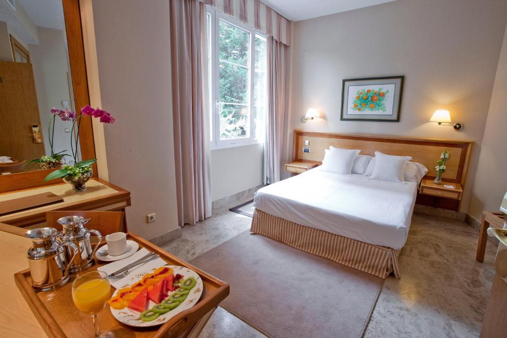 a hotel room with a bed and a tray of fruit at VP Jardín de Tres Cantos in Tres Cantos