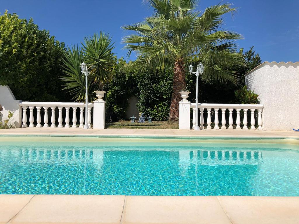 une piscine avec une clôture blanche et des palmiers dans l'établissement Villa du sud ouest, à Béziers