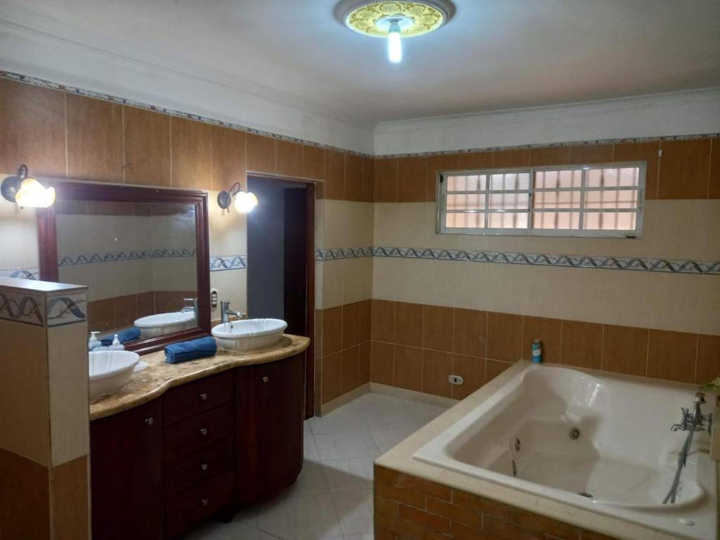 a large bathroom with two sinks and a tub at Penthouse con jacuzzi La cueva de los 3 ojos in Santo Domingo