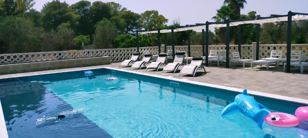 a swimming pool with chairs and a pool noodle in the water at Agriturismo "Terra D'Ulivi" in Porto Cesareo