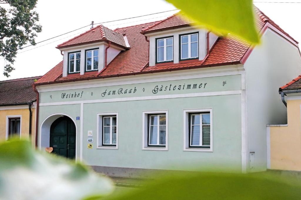 une maison blanche avec un toit rouge dans l'établissement Weinhof Gregor Raab, à Unterretzbach