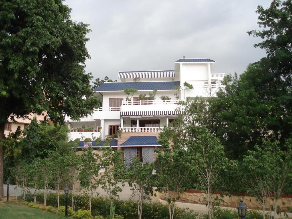 una casa bianca con degli alberi di fronte di Girisadan Boutique Hotel a Jaipur