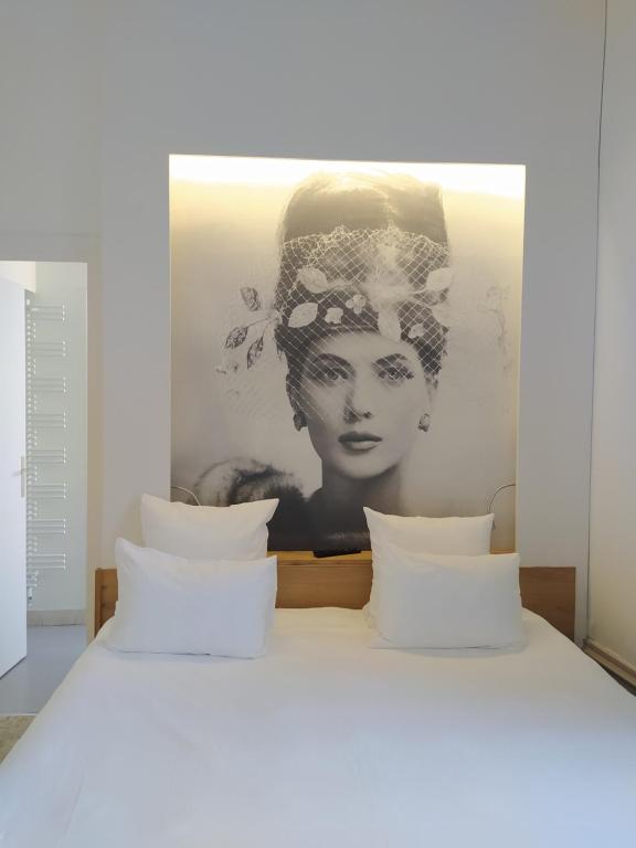 a painting of a woman is above a bed at Hôtel François 1er in La Rochelle
