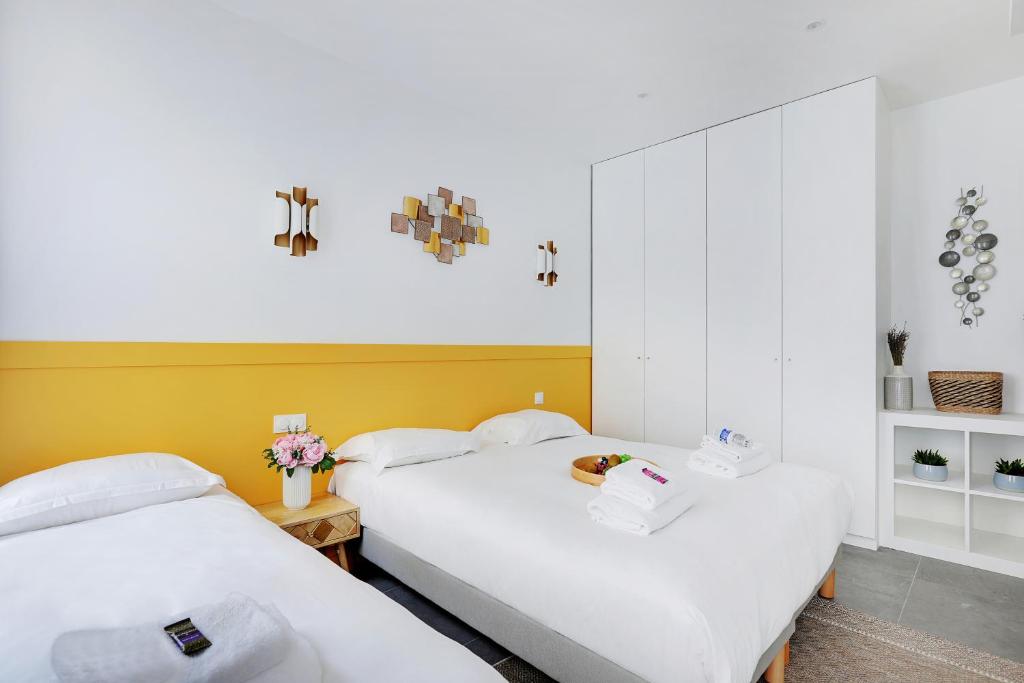 - 2 lits blancs dans une chambre aux murs jaunes dans l'établissement Charming apart -1BR-5P - République, à Paris