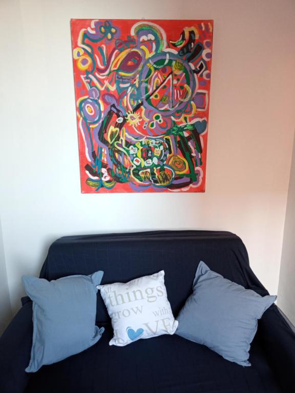 a painting hanging above a couch with pillows at Ofir, nice small unit, 123Eilat in Eilat