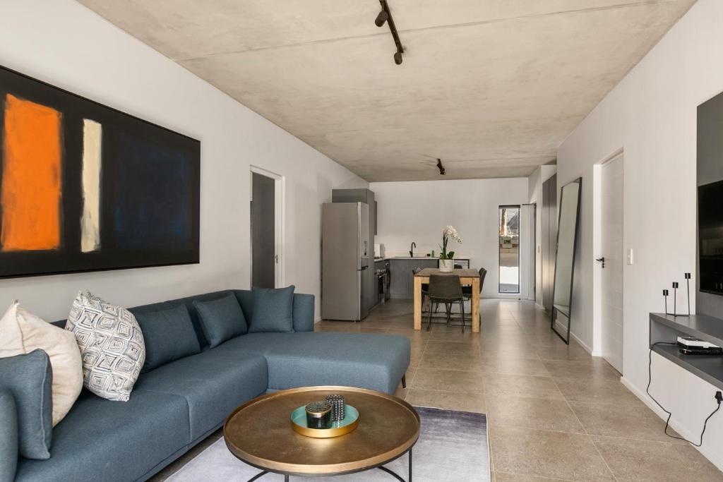 uma sala de estar com um sofá azul e uma mesa em Hyde Park House Apartments em Joanesburgo