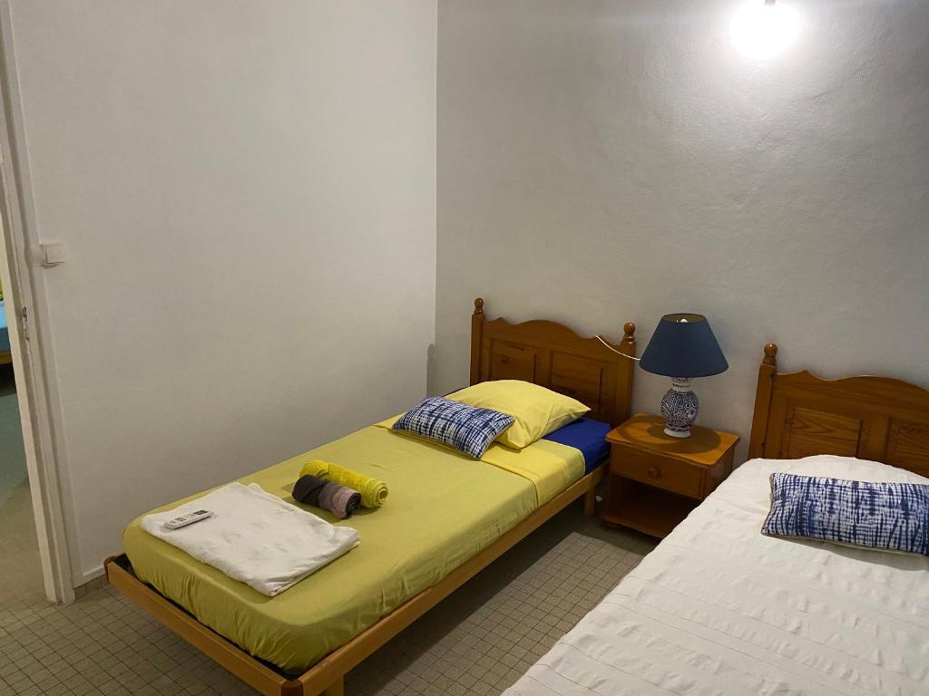 sypialnia z 2 łóżkami i lampką na stole w obiekcie Maison Petit Paradis w mieście Basse-Terre
