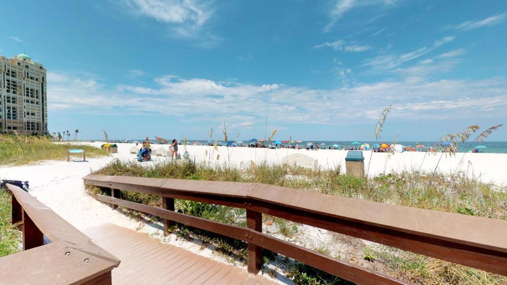 a wooden bench sitting next to a sandy beach at Totally Renovated Beachfront Condo at Apollo! in Marco Island