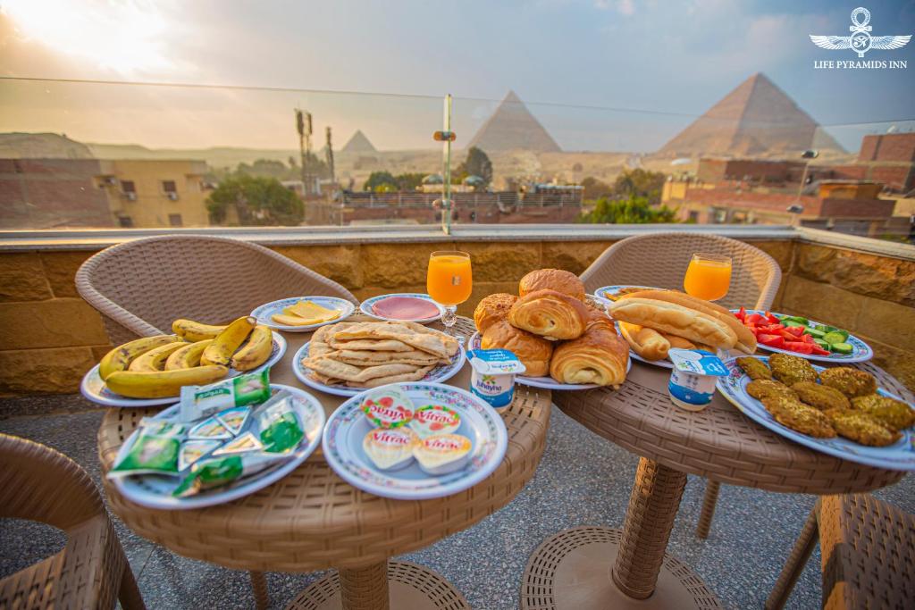 una mesa con platos de comida en la parte superior de un balcón en Life Pyramids Inn en El Cairo