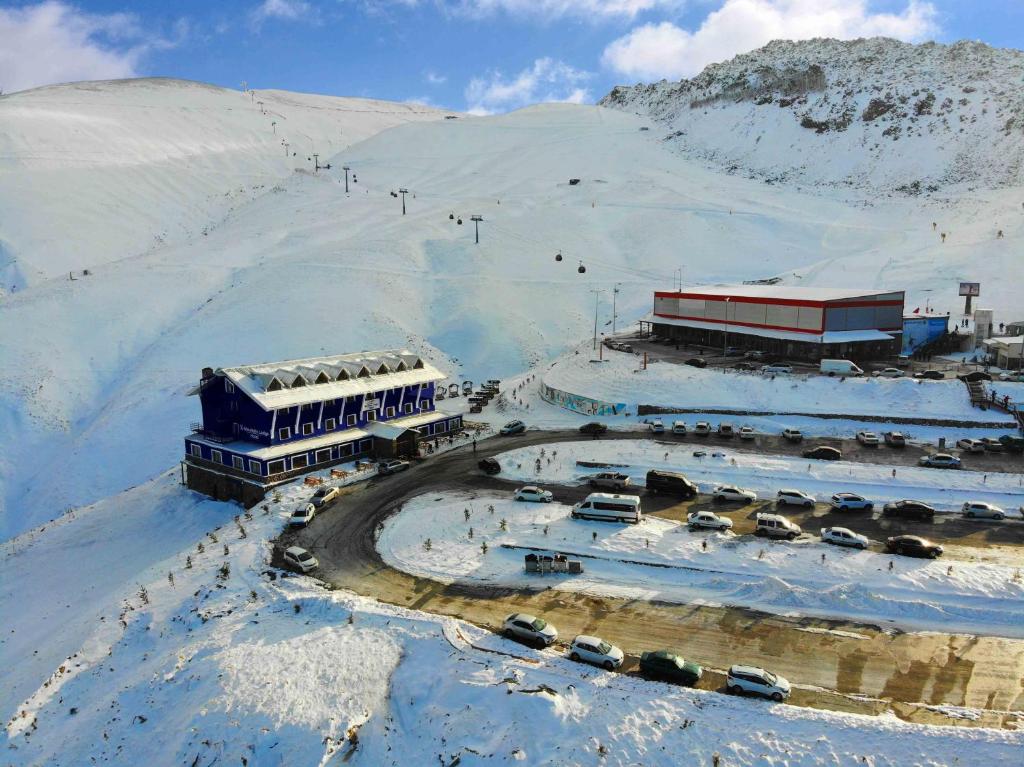 a snow covered mountain with cars parked in front of a building at X Mountain Lodge Erciyes in Erciyes