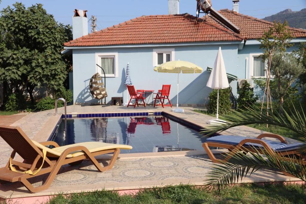 a house with a swimming pool with chairs and an umbrella at Villa Misli - Heart of Dalyan and Newly Renovated in Dalyan