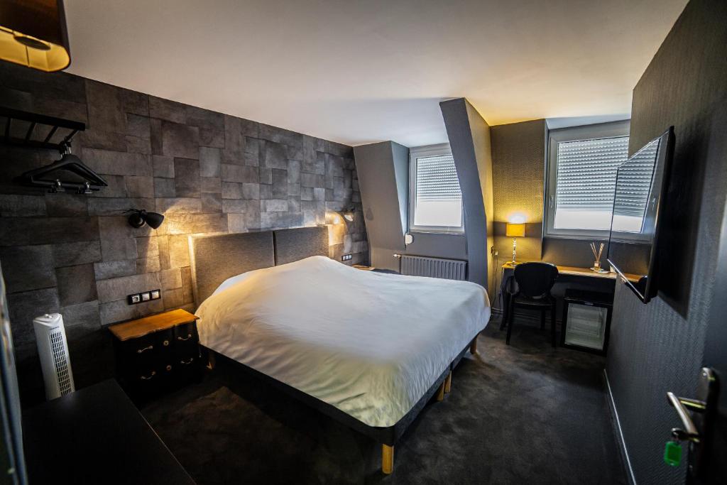 a small bedroom with a bed and a desk and windows at Cit'Hotel B Hotel in Béthune