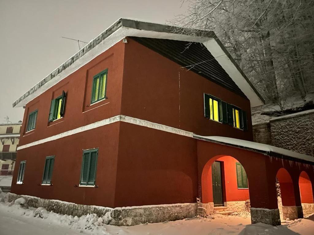 ein rotes Gebäude mit Schnee auf dem Boden in der Unterkunft La cantoniera dei 18 in Monte Terminillo