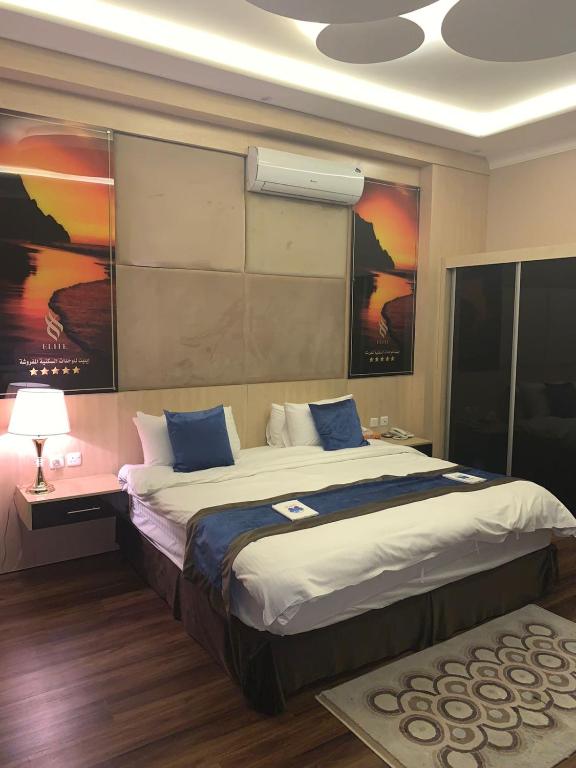 um quarto com uma cama grande e almofadas azuis em Elite Furnished Units em Riyadh