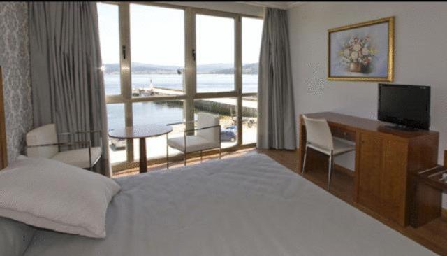 Pokój z łóżkiem, biurkiem i balkonem. w obiekcie Hotel As Brisas do Freixo w mieście O Freixo