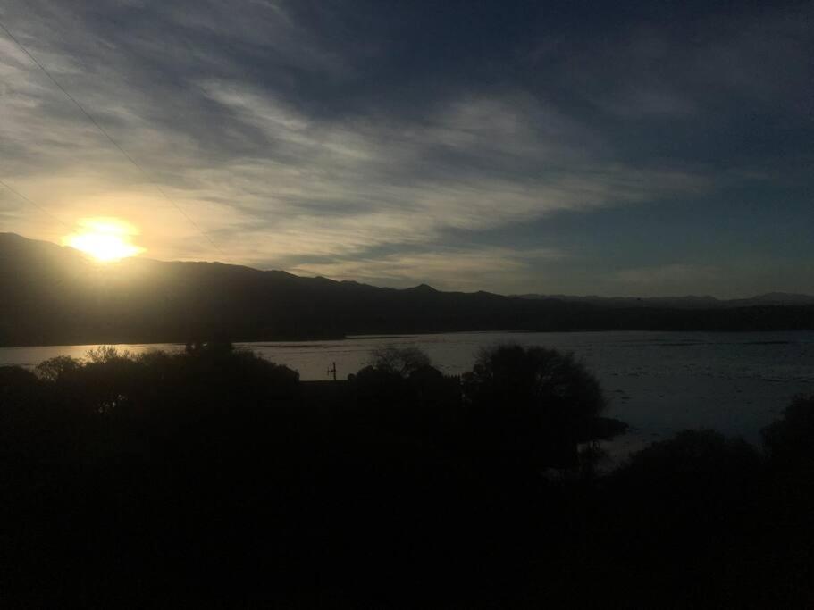 zachód słońca nad zbiornikiem wody ze słońcem na niebie w obiekcie Cabaña a orillas del Lago w mieście Tarija