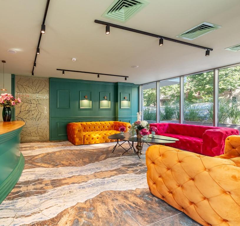 una sala de estar con muebles de color amarillo y rojo y paredes verdes. en Tomis Garden Aparthotel Bucuresti en Bucarest