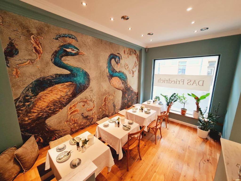 um restaurante com mesas brancas e um mural de pavão em Das Friedrich em Knittelfeld