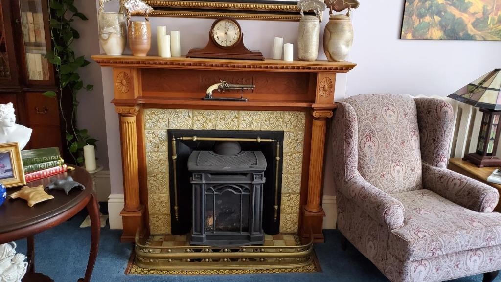 a living room with a fireplace and a chair and a clock at The Lark & Loon Inn in Annapolis Royal
