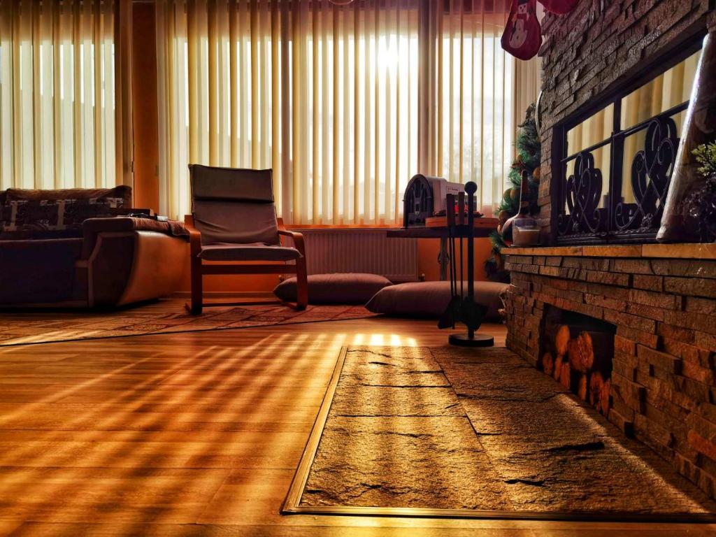 a living room with a fireplace and a chair at Къща За Гости Уют Guest House Cozy in Starosel