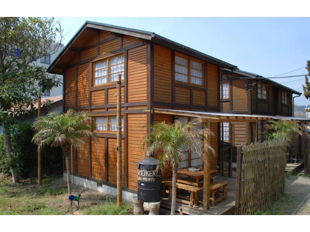 a wooden house with palm trees in front of it at Cottage Izu,com - Vacation STAY 07073v in Minamiizu