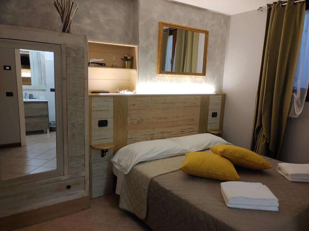 a bedroom with a bed with yellow pillows and a mirror at Bed & Breakfast Ca'Bassano in Bassano del Grappa