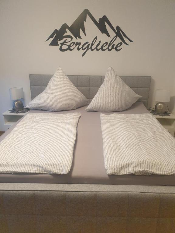 ein Bett mit zwei Kissen und ein Schild an der Wand in der Unterkunft Haus Guem in Ehrwald