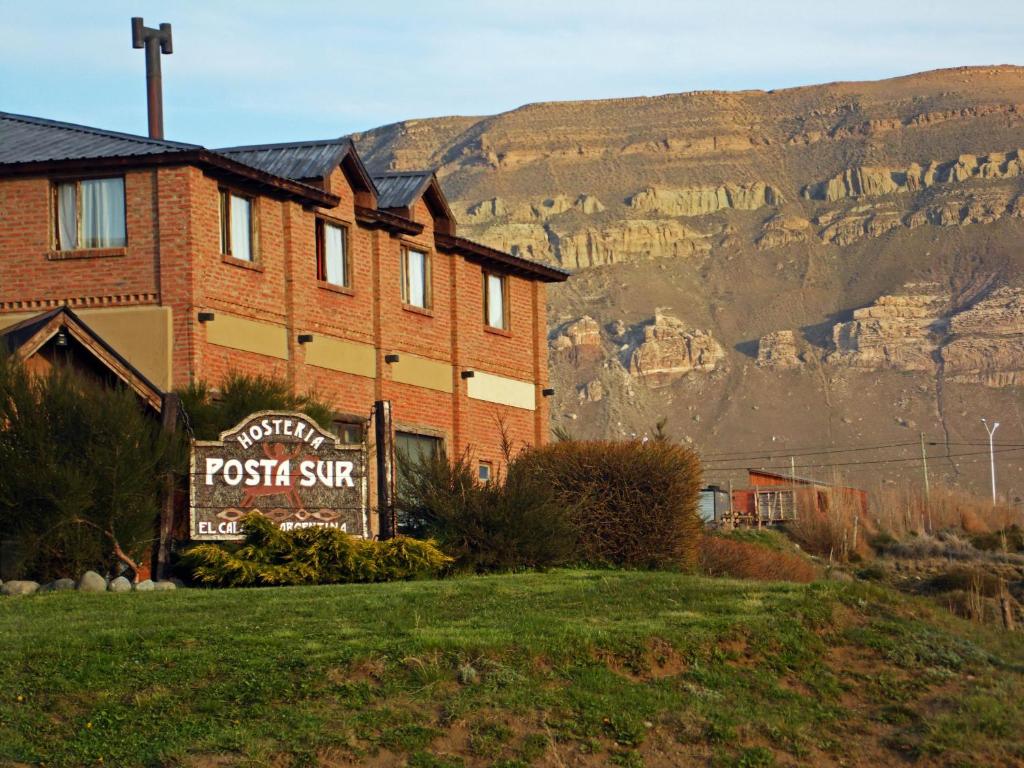 a building with a sign in front of a mountain at Hosteria Posta Sur in El Calafate