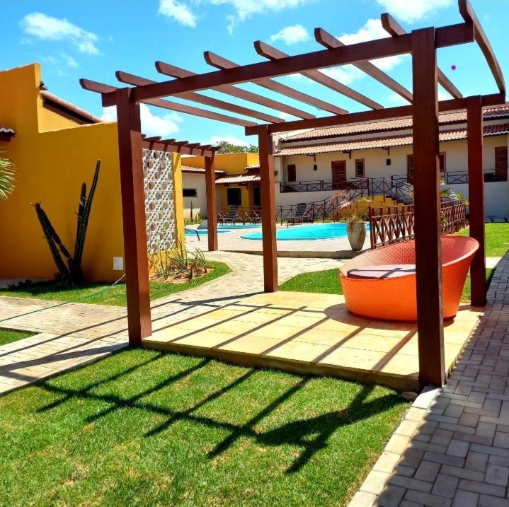 pérgola de madera en un patio con piscina en Pousada Império en São Miguel do Gostoso