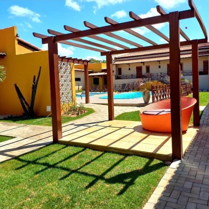 a wooden pergola in a yard with a pool at Pousada Império in São Miguel do Gostoso