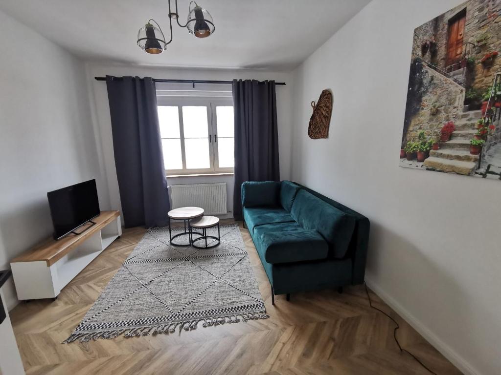 ein Wohnzimmer mit einem grünen Sofa und einem TV in der Unterkunft Apartament Black&White in Jelenia Góra