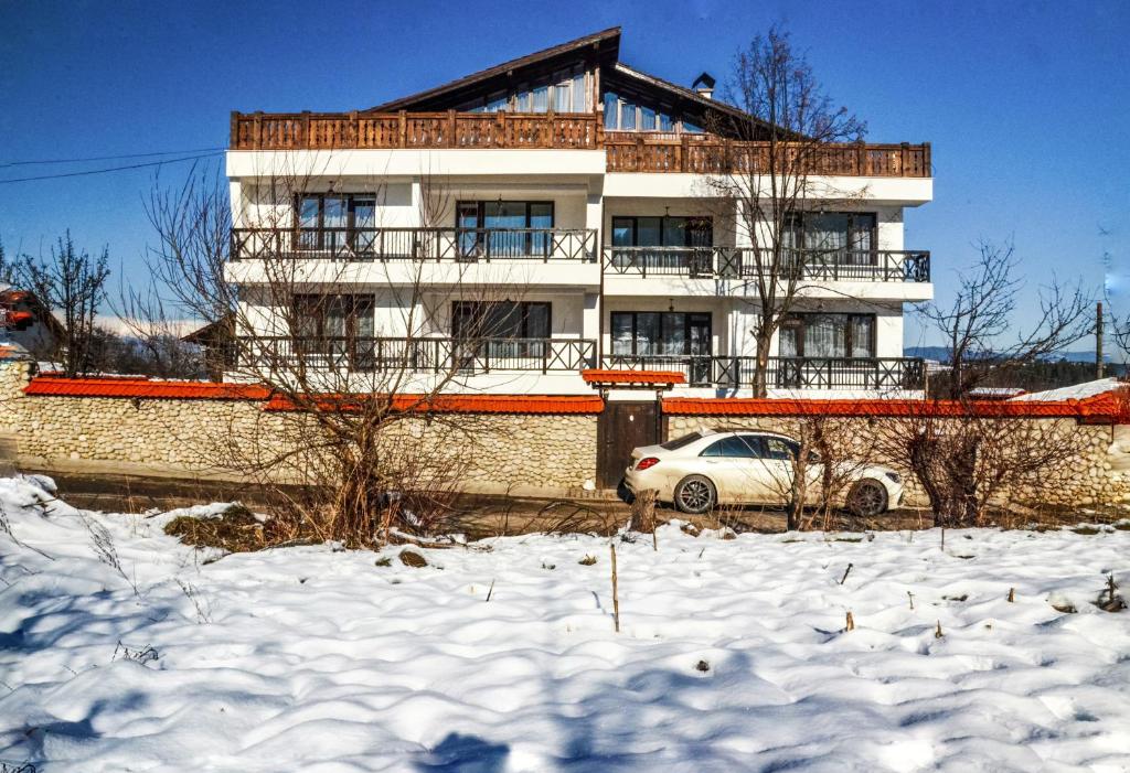 a building with a car parked in the snow at Family hotel Andreev in Dobrinishte