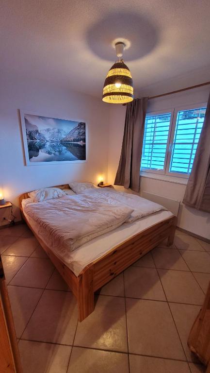 um quarto com uma cama grande num quarto com janelas em Appartement avec terrasse ensoleillée em Gruyères