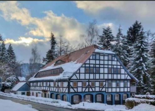 um grande edifício com neve em cima em Haus zur alten Bimmelbahn em Kurort Jonsdorf