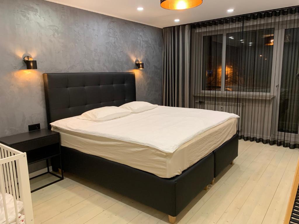 a bedroom with a large bed with a black headboard at Tammsaare Luxury Apartment in Pärnu