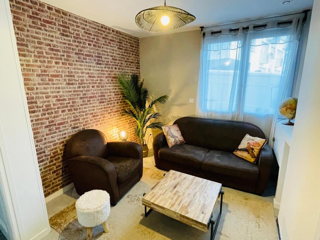 a living room with two couches and a brick wall at Superbe T3 proche de l'hypercentre de Lorient avec terrasse in Lorient