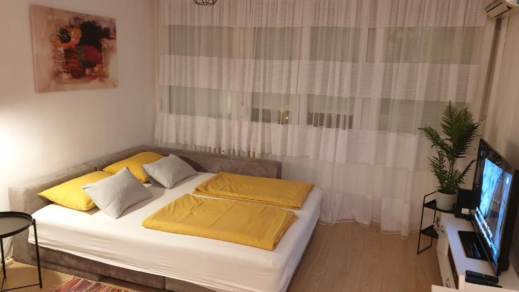 Apartman Utrine في زغرب: غرفة نوم بسرير ومخدات صفراء وتلفزيون