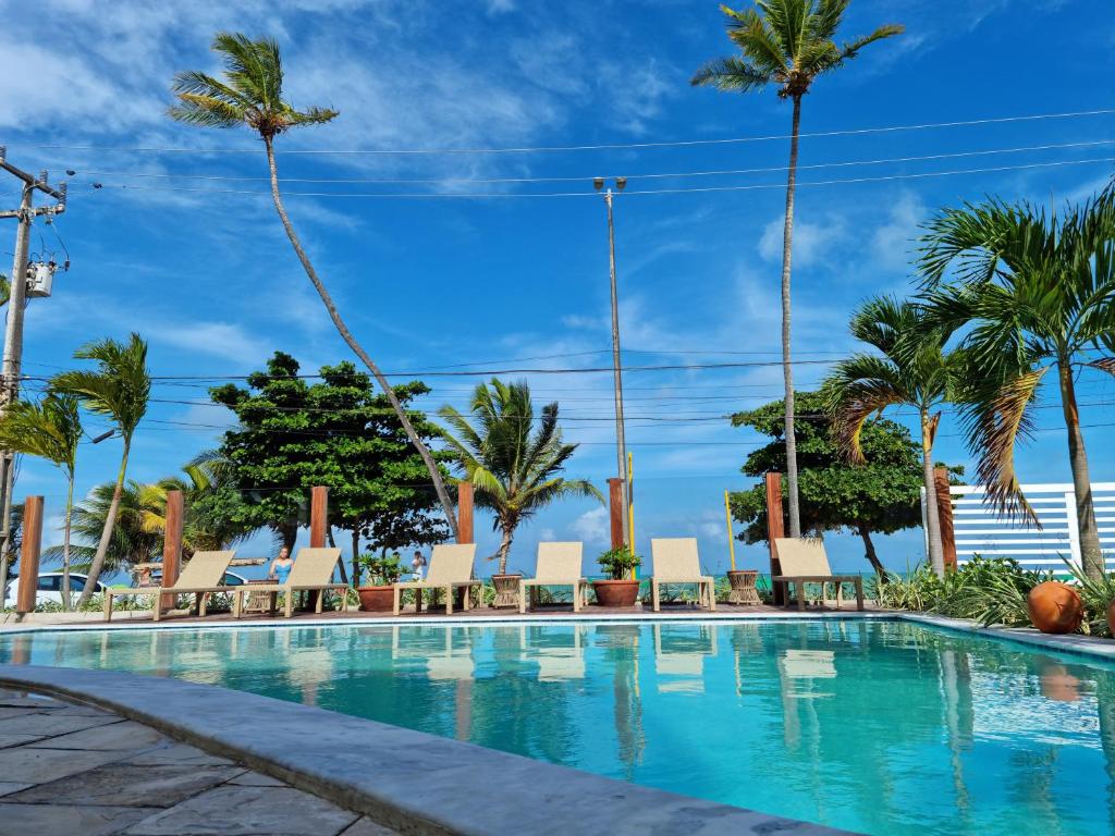 a swimming pool with chairs and palm trees at Kastel Jampa Hotel in João Pessoa