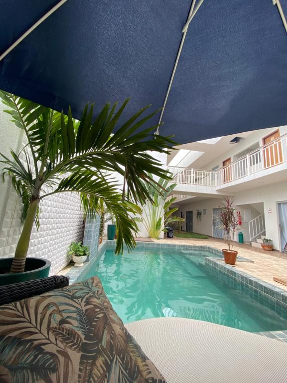 a pool with a palm tree and an umbrella at Ventanas Hotel Boutique in Carolina