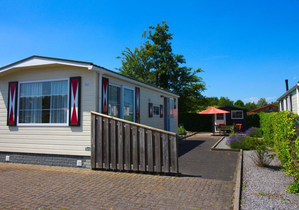 a small house with a fence on a brick driveway at Chaletparc Krabbenkreek Zeeland - Chalet 152 in Sint Annaland